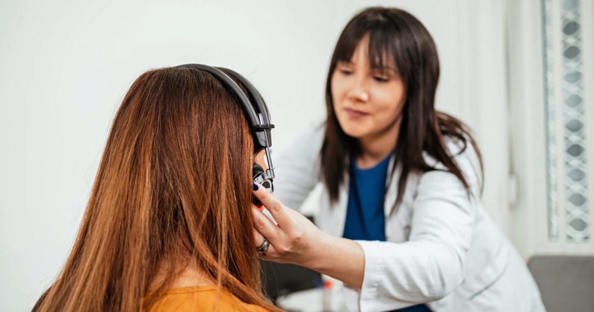 Audiologist performing ear exam