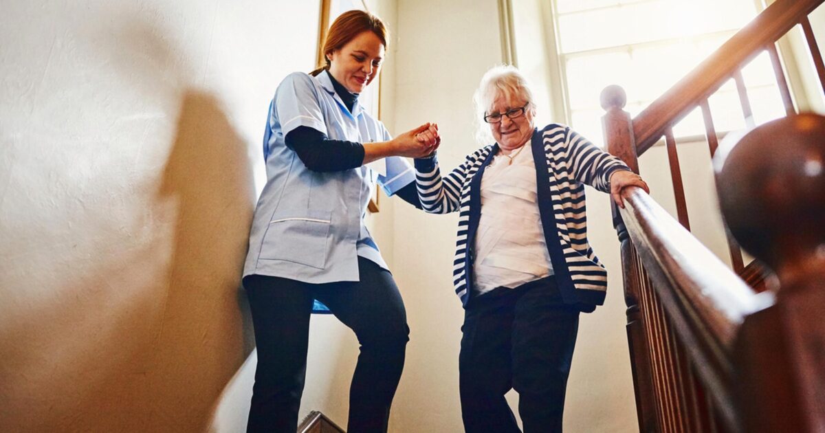 CNA helping patient down stairs