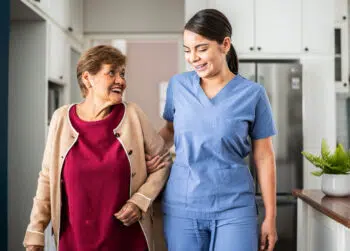 CNA or HHA helping home care patient with walking