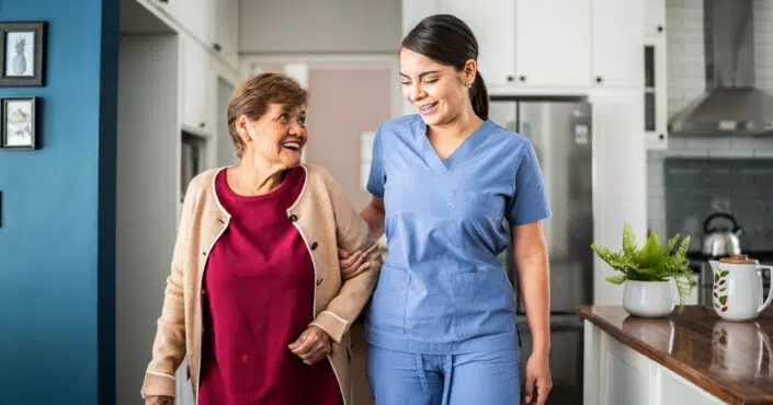 CNA or HHA helping home care patient with walking