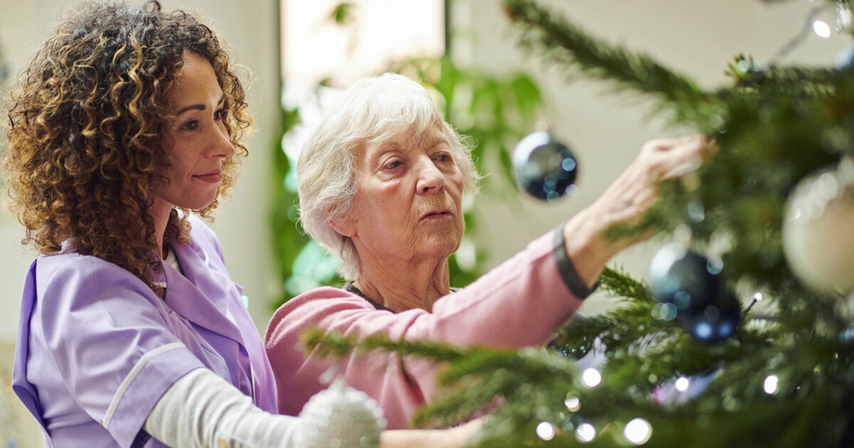 Nurse helping patient decorate tree